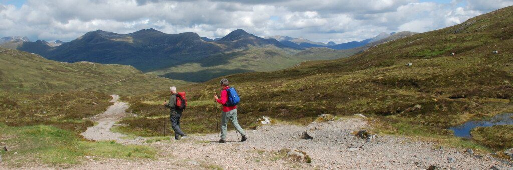 Two hikers with Scottish Highlands in the background on the West Highland Way.