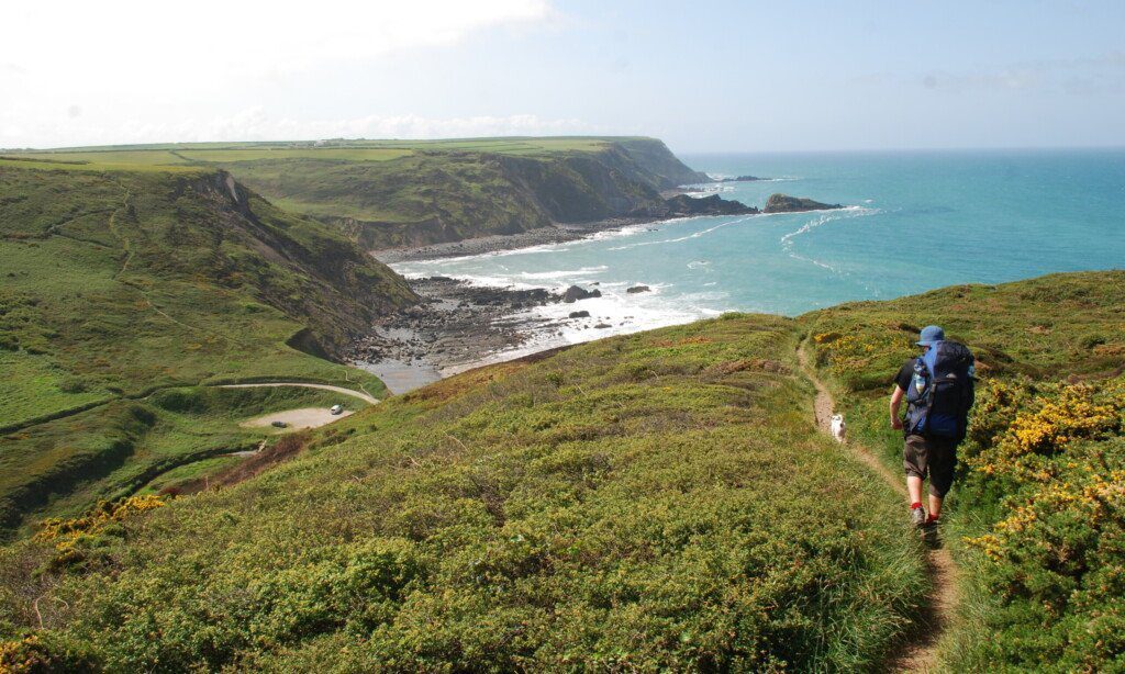 Hiker heading towards the Devon-Cornwall Bude on the final leg of the first section of the South-West Coast Path.