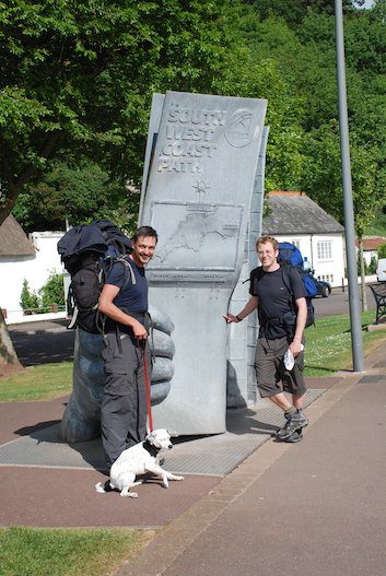 Two hikers plus dog by monument marking start of South-West Coast Path, at Minehead. 