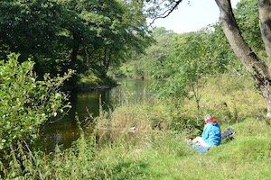 Beginner hiker sits by the River Wharfe on the Dales Way