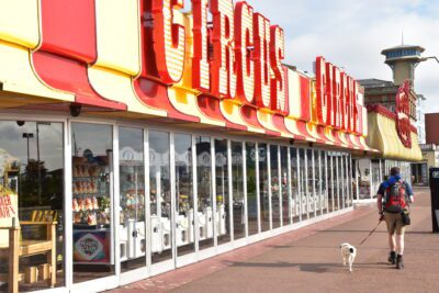 Hiker and dog walk past Circus Circus Amusement arcade on the seafront at Great Yarmouth