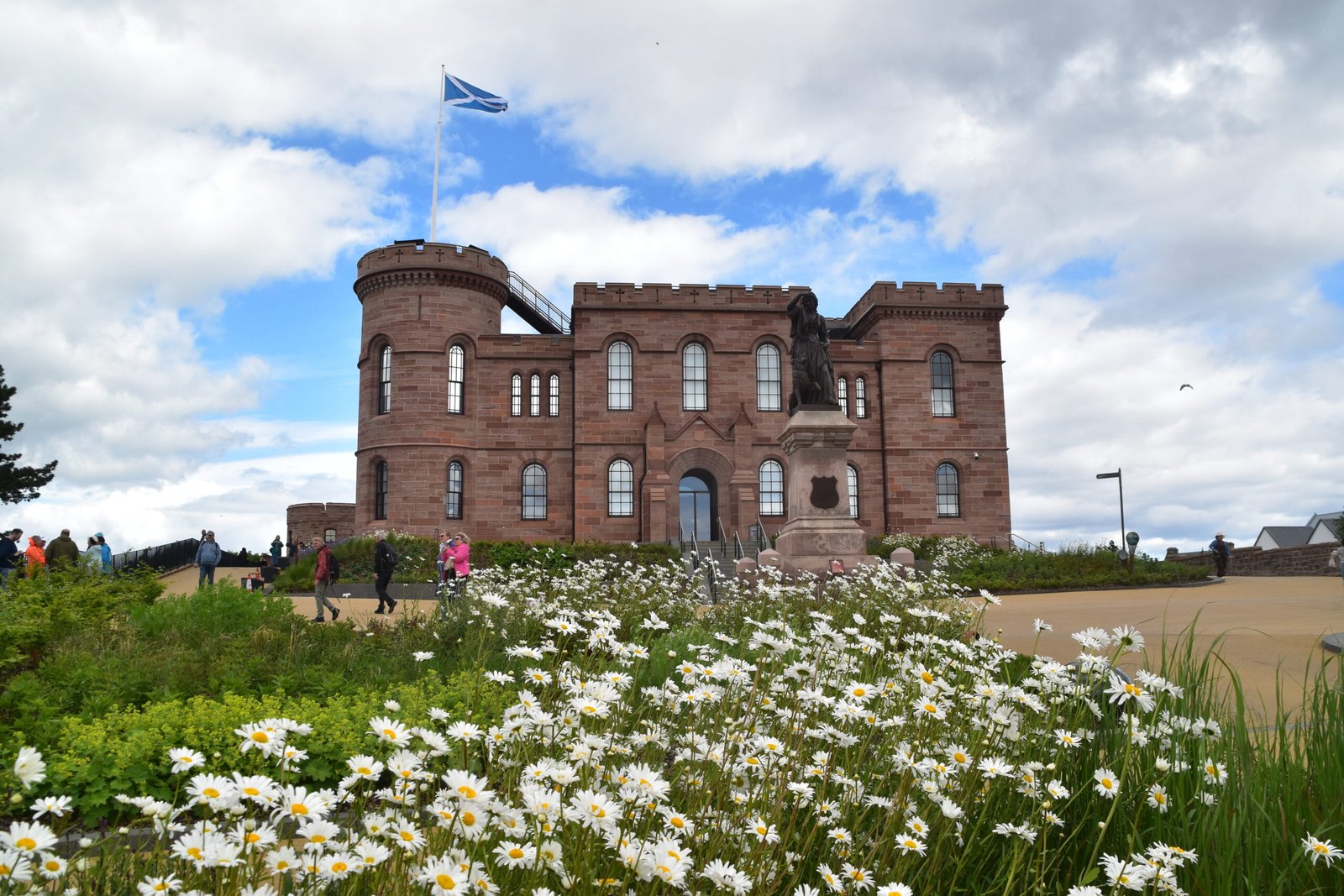 Inverness Castle flying Scottish flag daisies in foreground